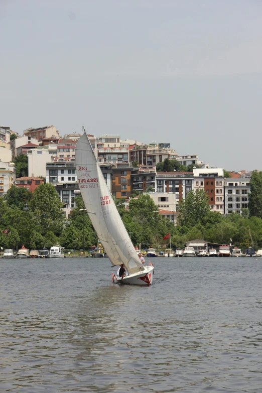 a sail boat is on the water near a big city