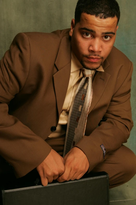 a young man wearing a brown jacket and striped tie