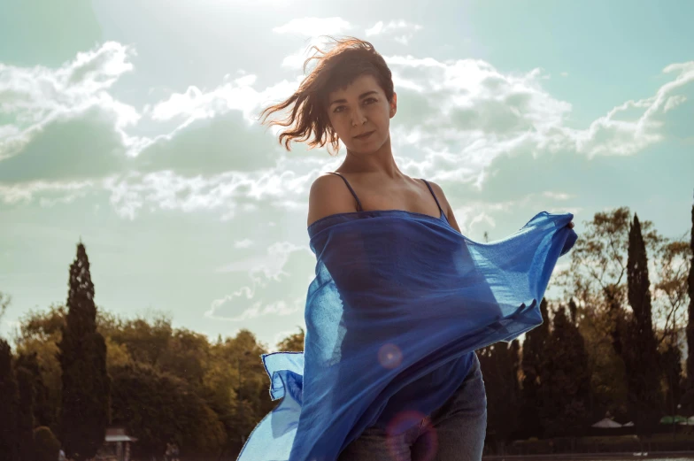 a beautiful woman standing outside with a blue scarf on her arms