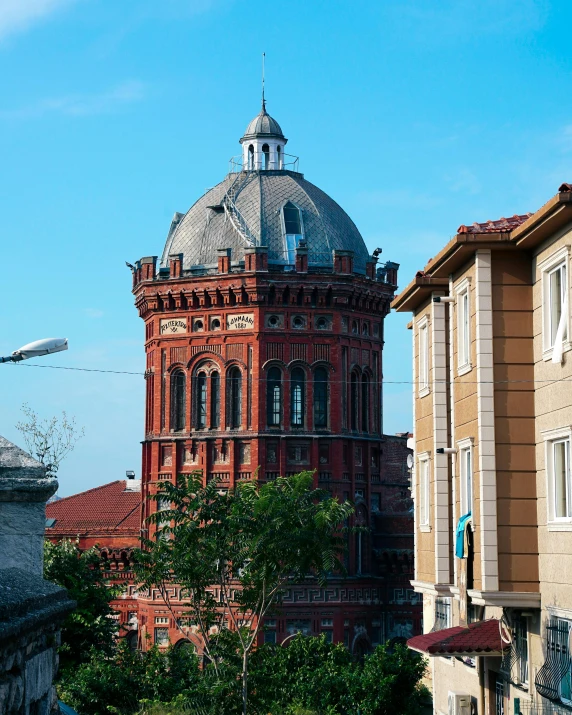 an old red building with a large dome in the middle of a town