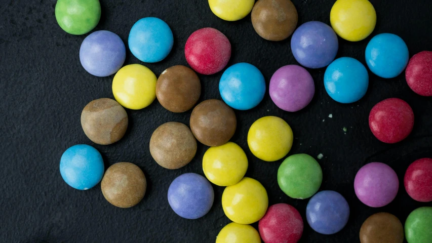 colorful candies displayed on black surface with scattered petals