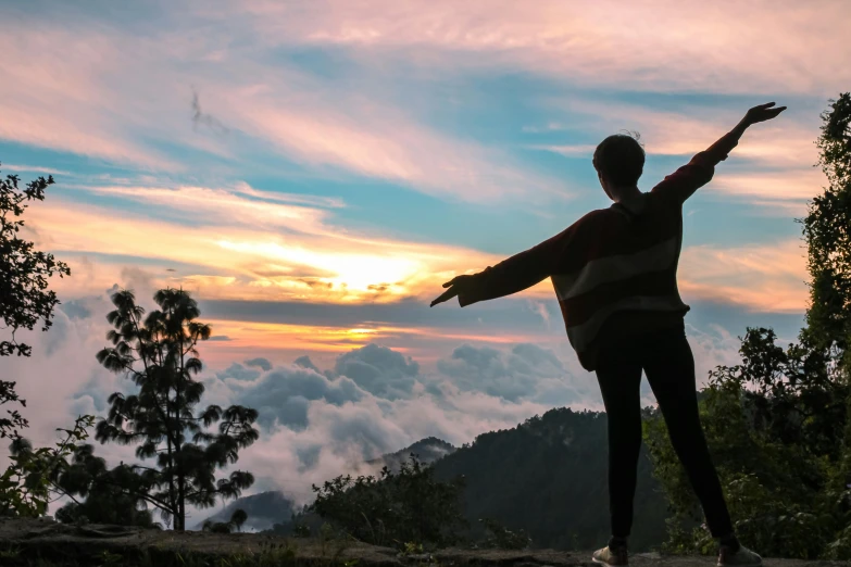 a person standing on top of a mountain with their arms outstretched