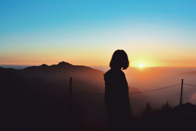 the silhouette of a person overlooking the mountain range