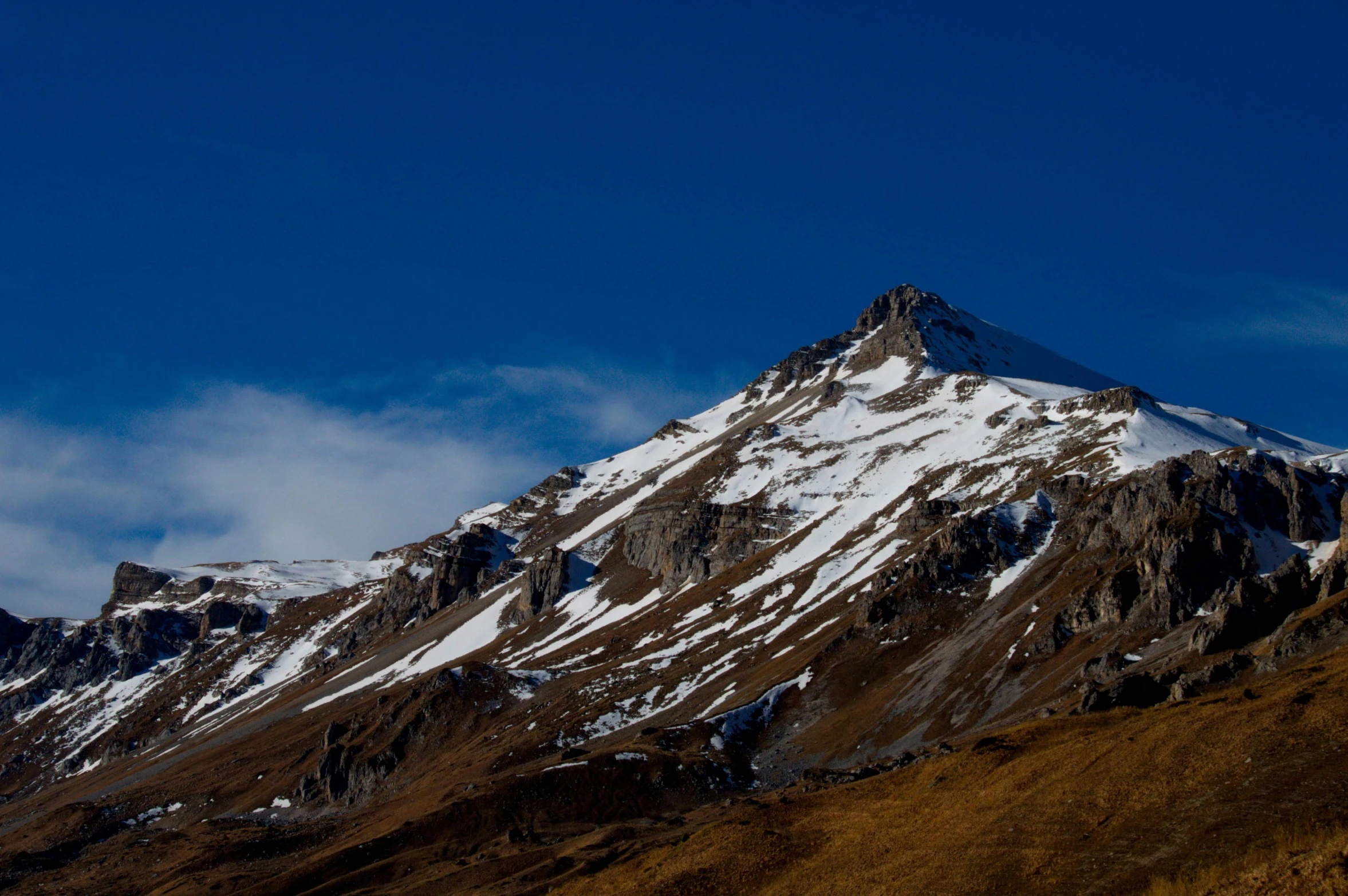 a large mountain range covered in snow against a blue sky