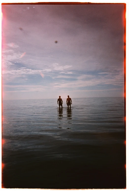 two people wading through the ocean with a dog on their back