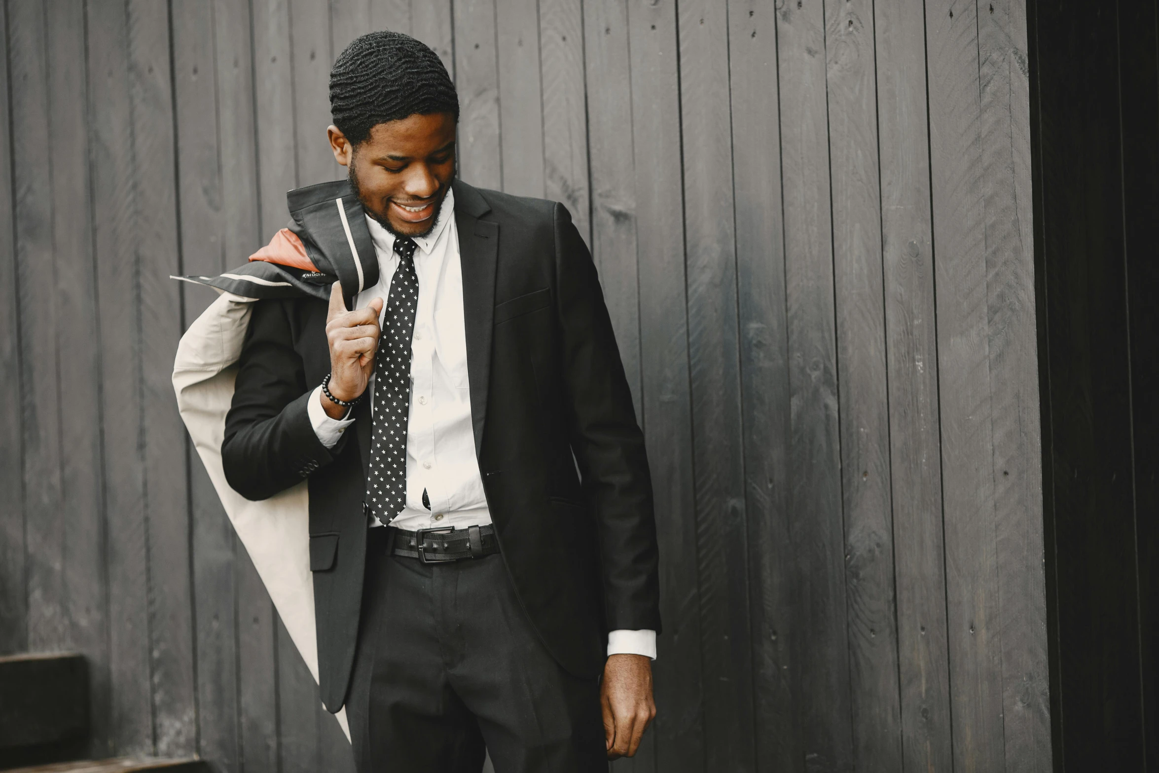 a man is walking down the street wearing a suit and holding a coat