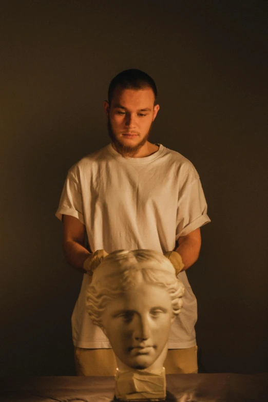 man standing by a bust of a male in white shirt