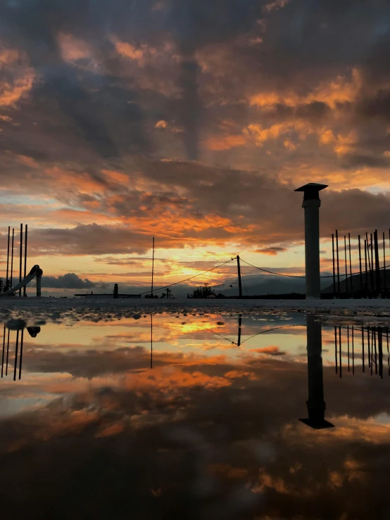 a sunset and some tall buildings reflecting in water