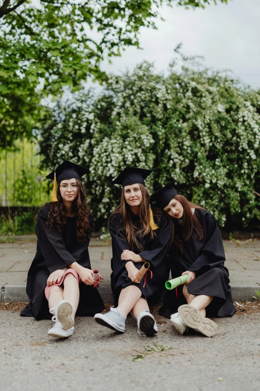 three beautiful young women sitting in graduation regalia