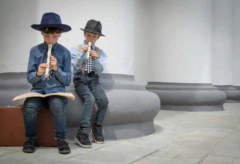 two young children sitting on a bench playing guitars