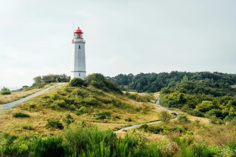 a very tall light house on a grassy hill