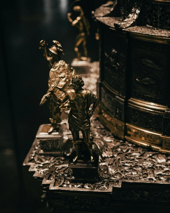 three golden metal figures sitting on top of a marble slab