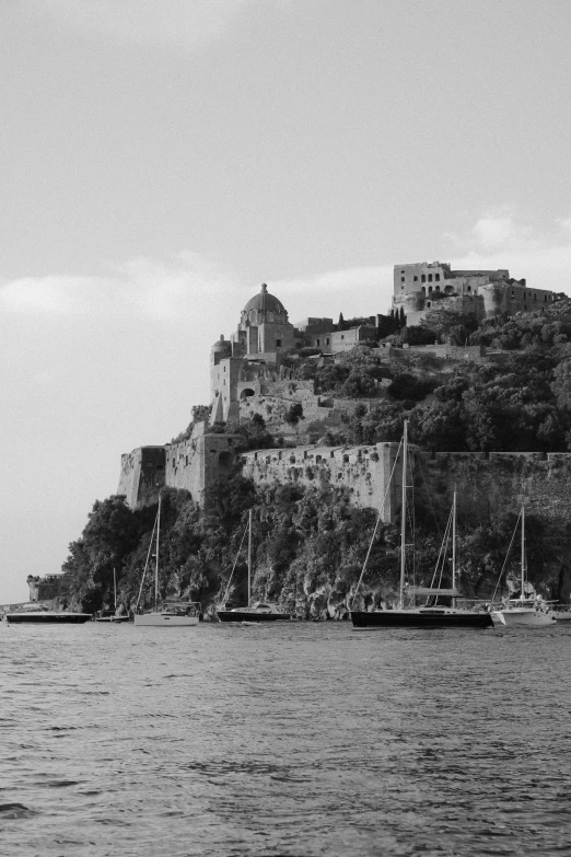 many small boats on the water near a mountain