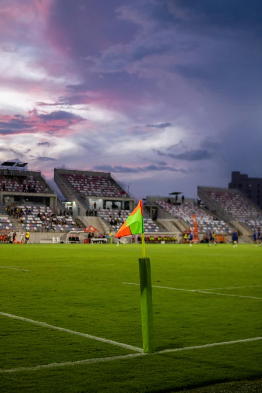 a soccer field with a green grass field and sky with clouds