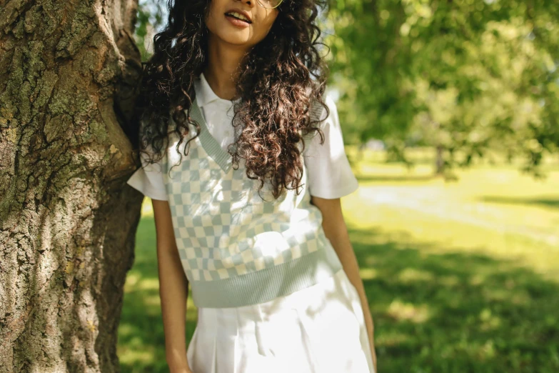 a beautiful young woman standing next to a large tree