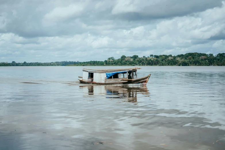 a houseboat in the middle of the ocean with trees in the distance