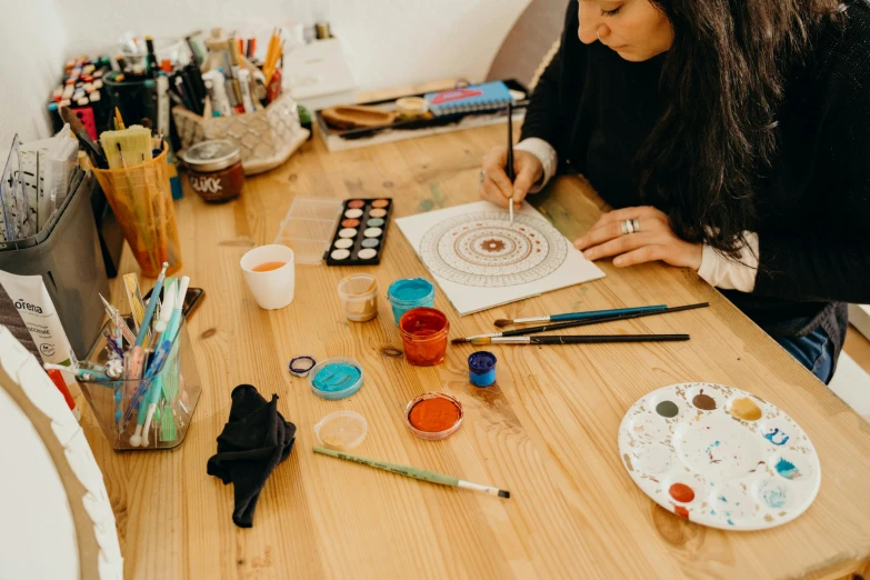 a woman is sitting at a table painting