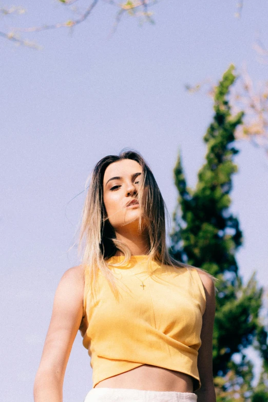 a woman wearing yellow and white shorts in front of trees