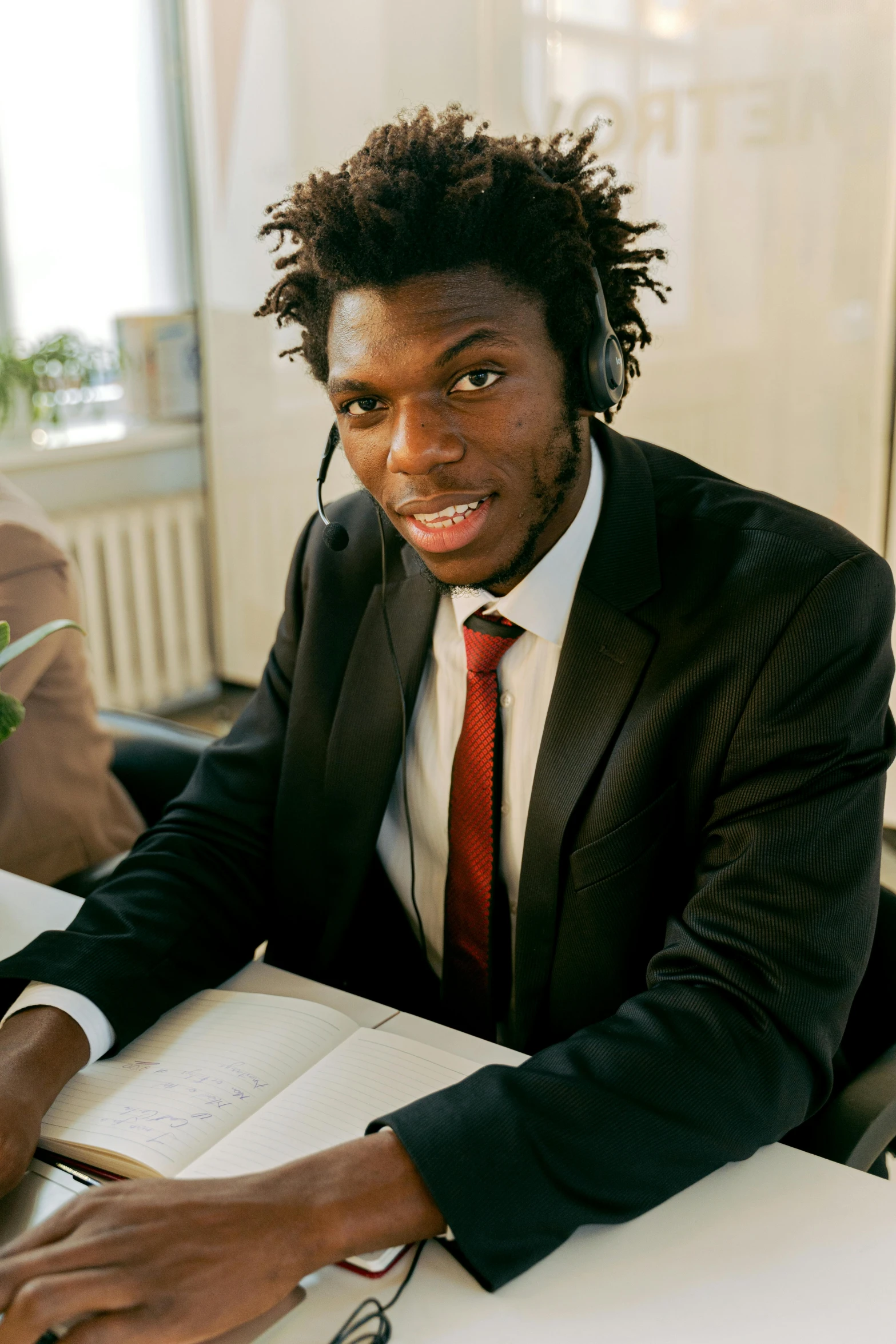 a young african man wearing headphones, reading a book