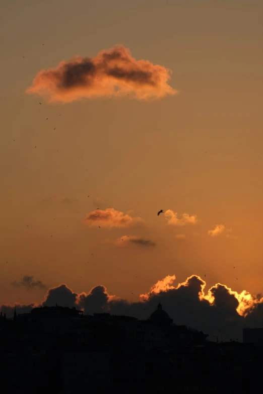 a large, orange cloud in the sky at sunset