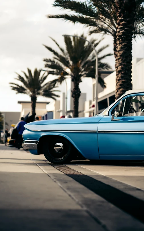 blue classic car sitting on the side of a road