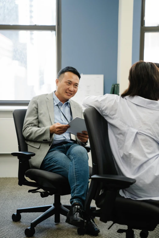 a person in a chair holding up a piece of paper with a man watching