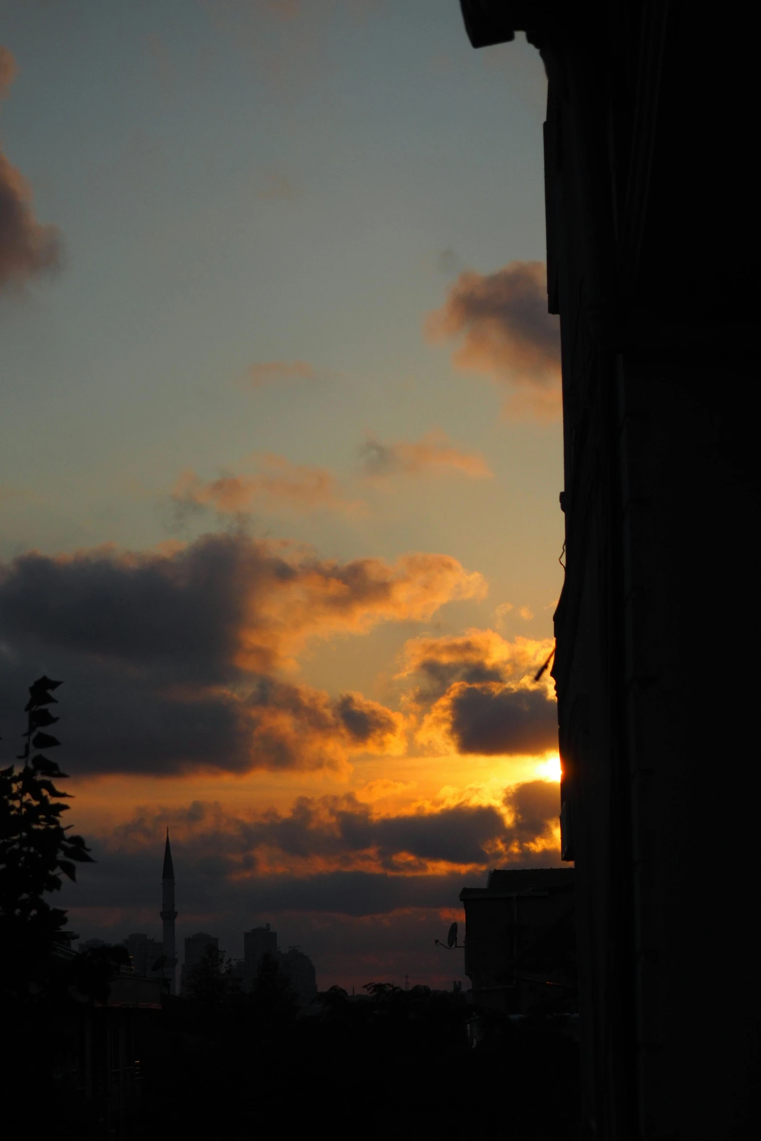 the sunset in a city is pictured through clouds