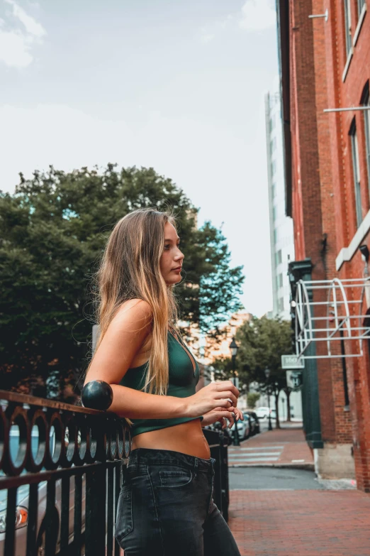 beautiful woman in high waist jeans leaning on fence