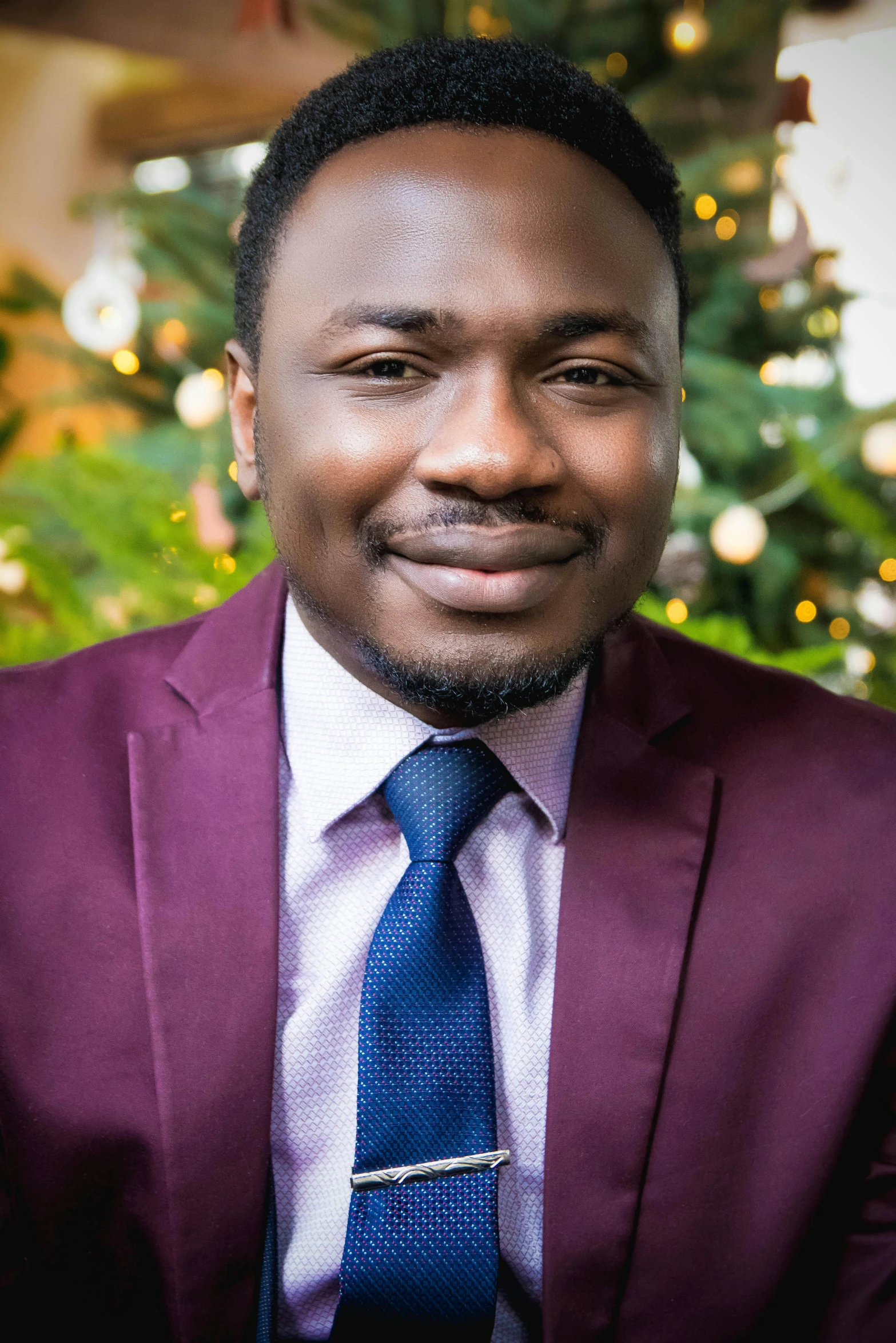 a smiling young black man in a purple suit