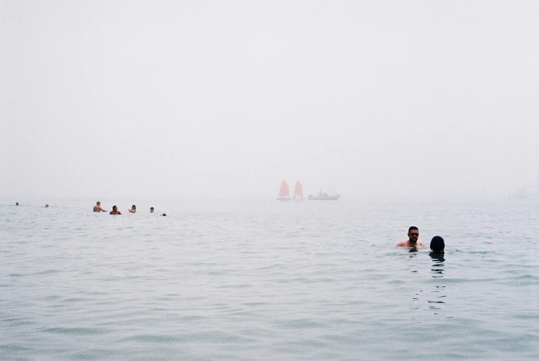 two women swims in a body of water while others play around