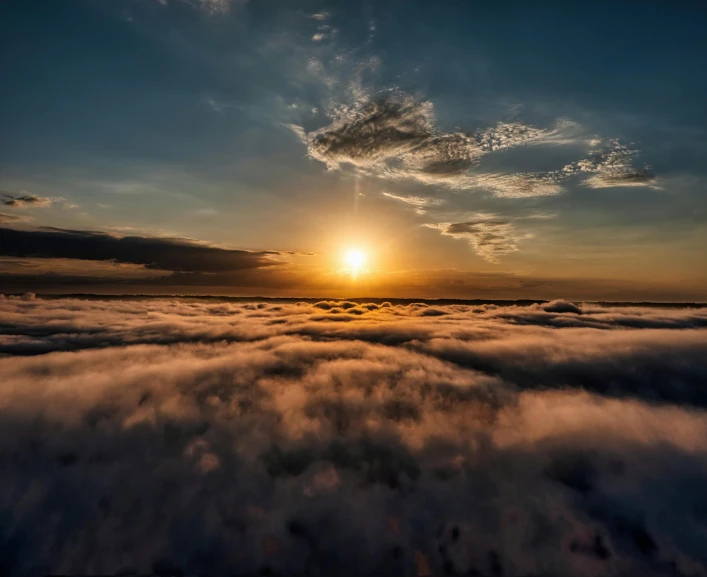 the sun shining over clouds in a dark sky