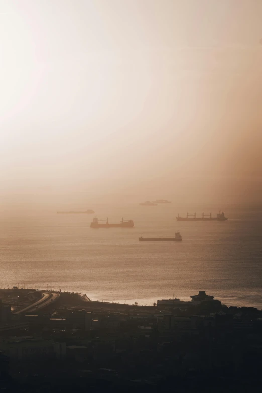 three ships float on a calm ocean at sunset