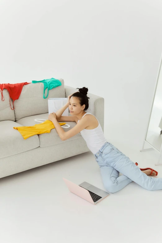 a young woman sits on the floor next to a sofa