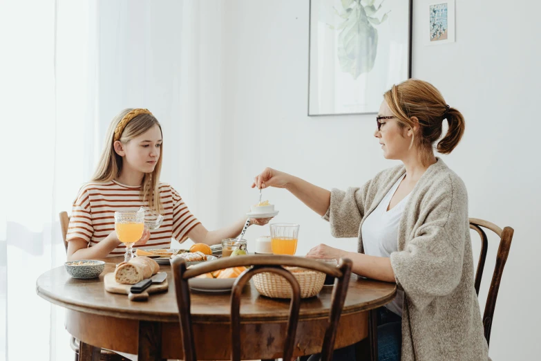 two young ladies sitting at a dining table having breakfast