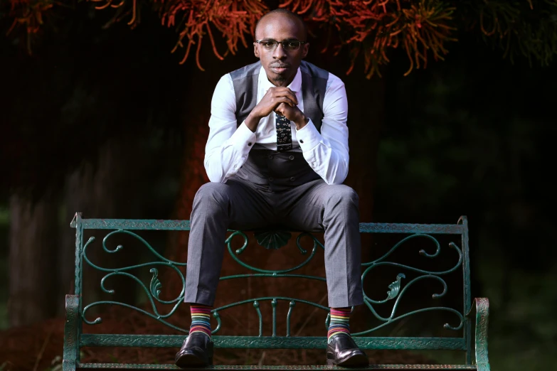 a man in grey and white shirt sitting on green bench