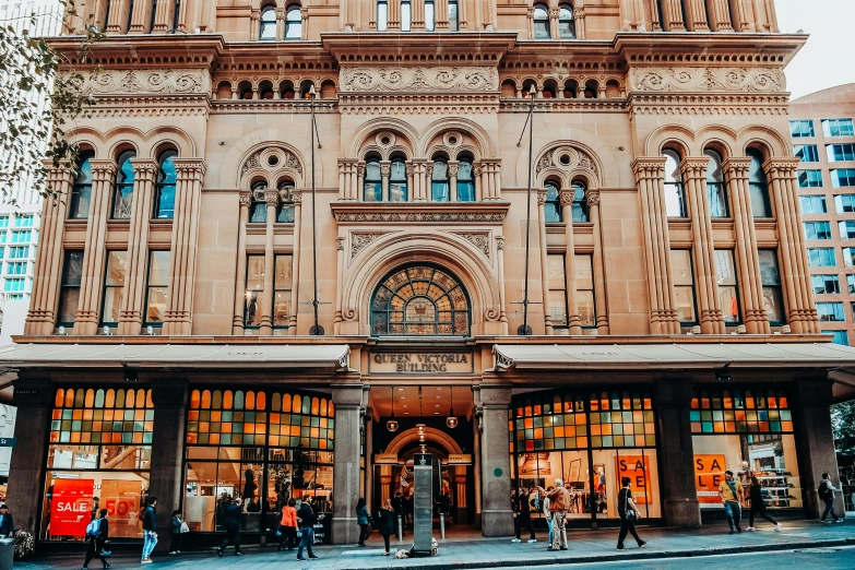 an old fashioned building with a bunch of people walking in front of it