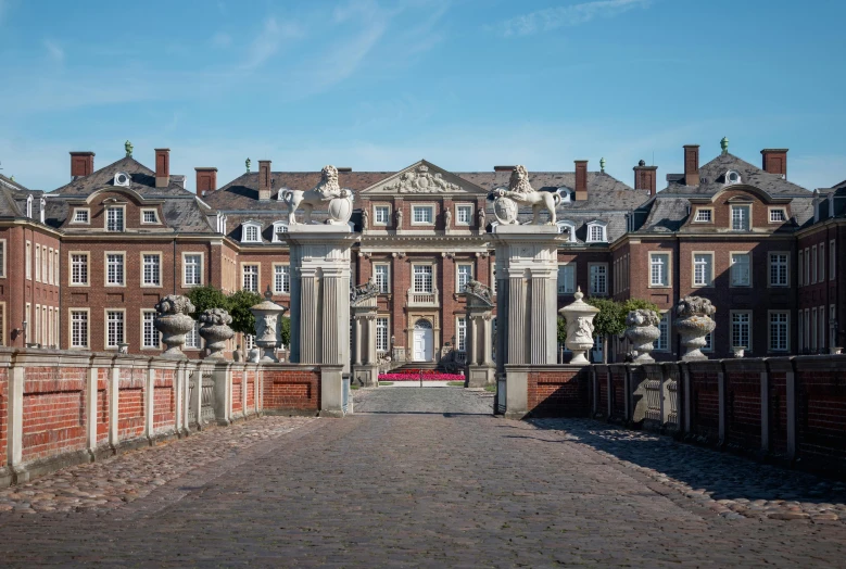 a castle like building stands with a brick driveway