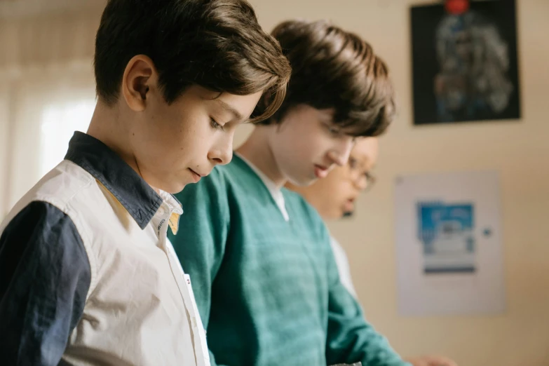 a  stands in front of three other boys in a room