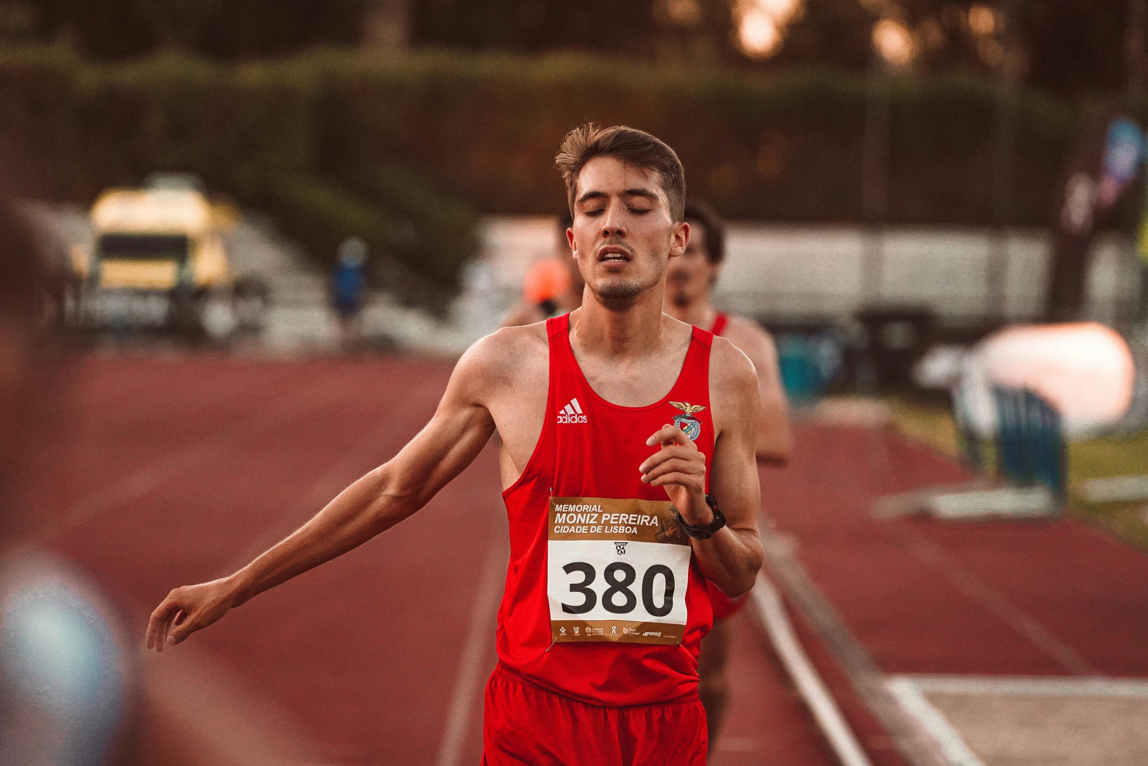 a male athlete is seen wearing red and running on the track