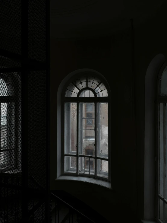 a dark stairwell with arched windows at night time