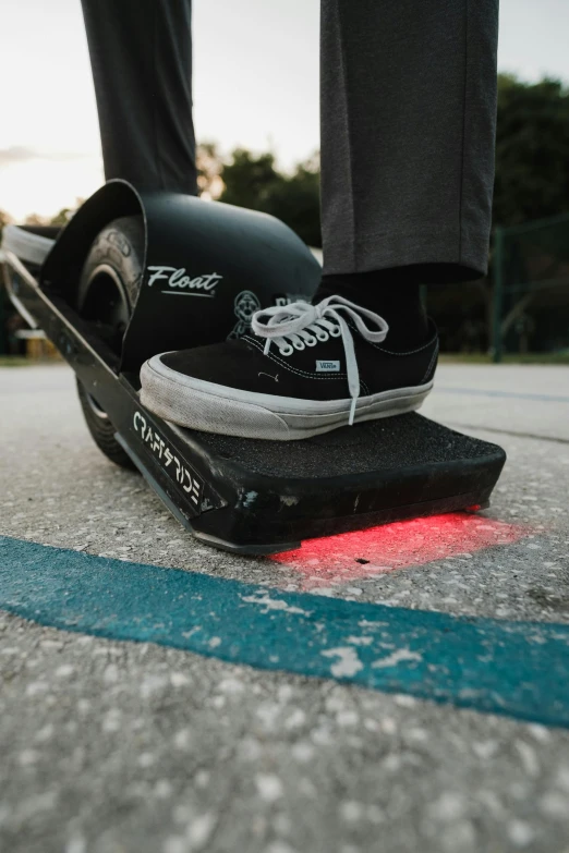 a skateboarder's feet in black sneakers and grey pants