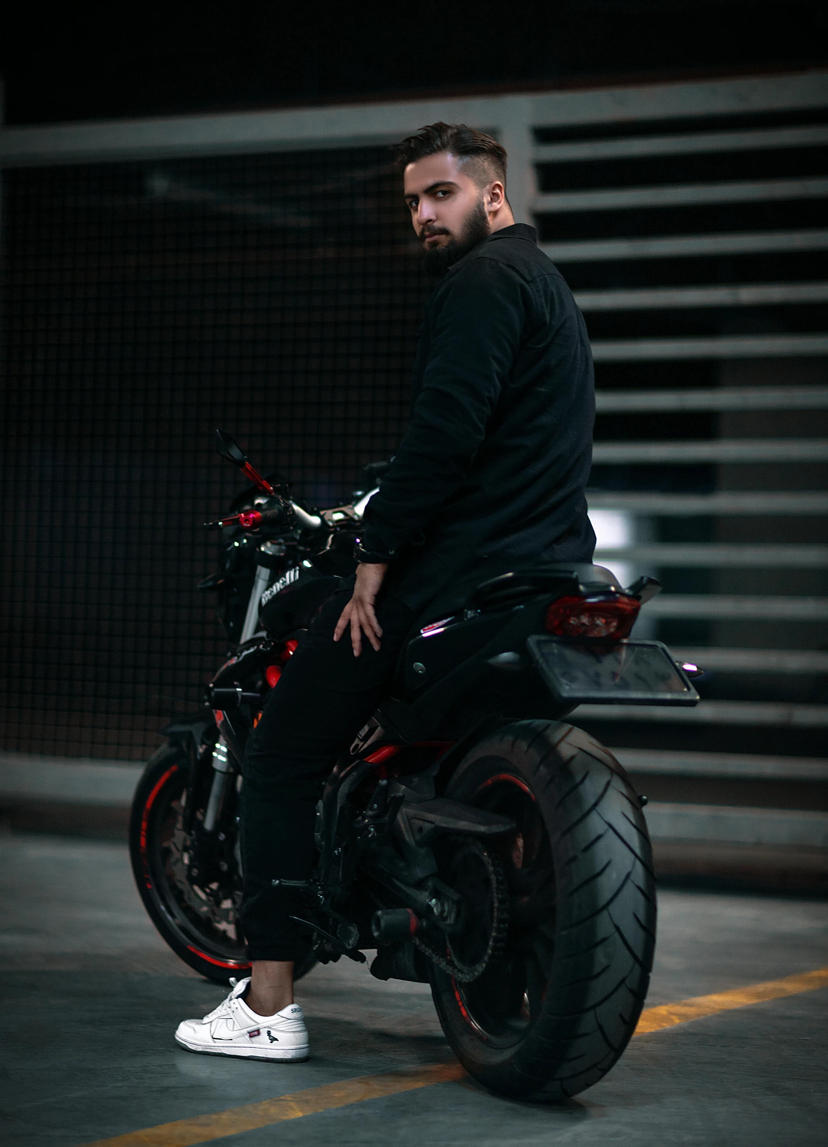 a man with a beard standing next to a motorcycle