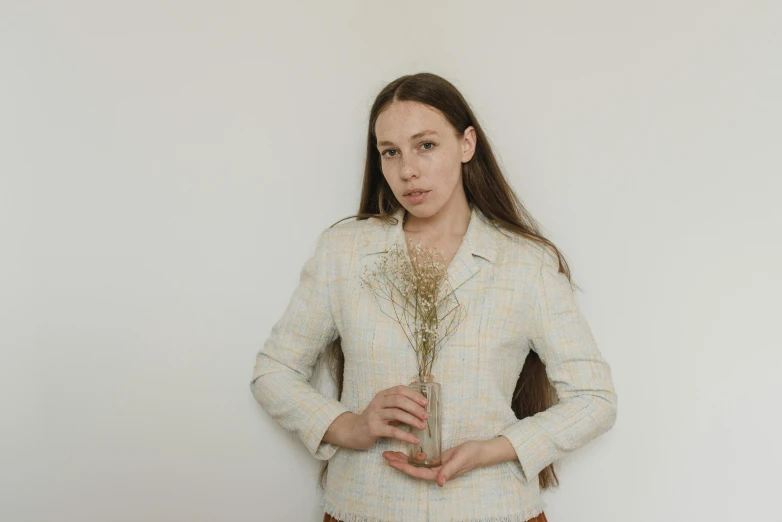 a woman in jacket holding up a small piece of jewelry