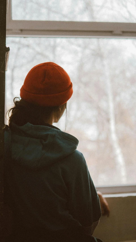 a person wearing a red hat sitting by a window