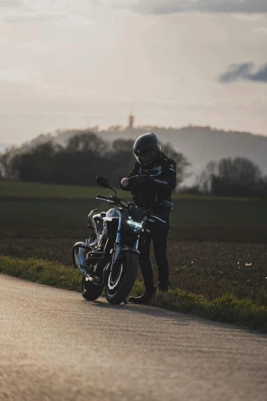 man in helmet standing by motorcycle on roadway during daytime