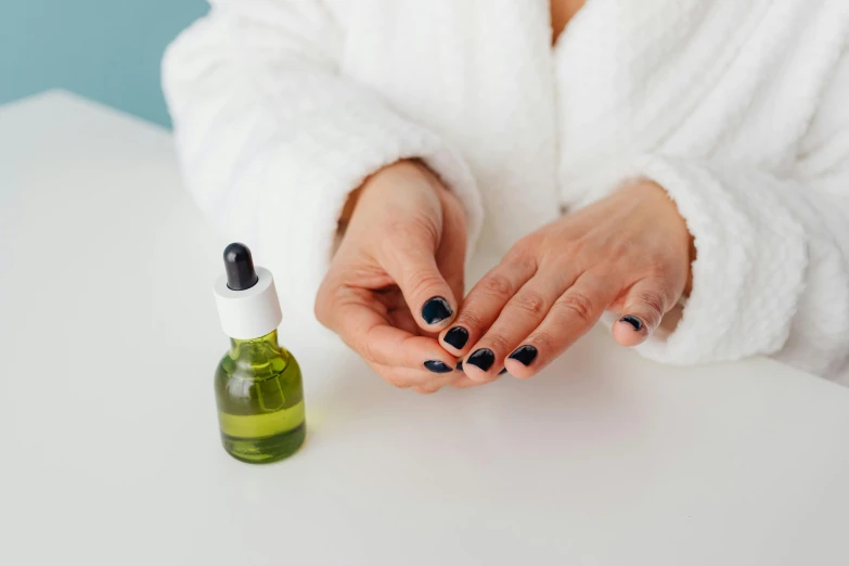 the woman is holding onto her nails next to the bottle