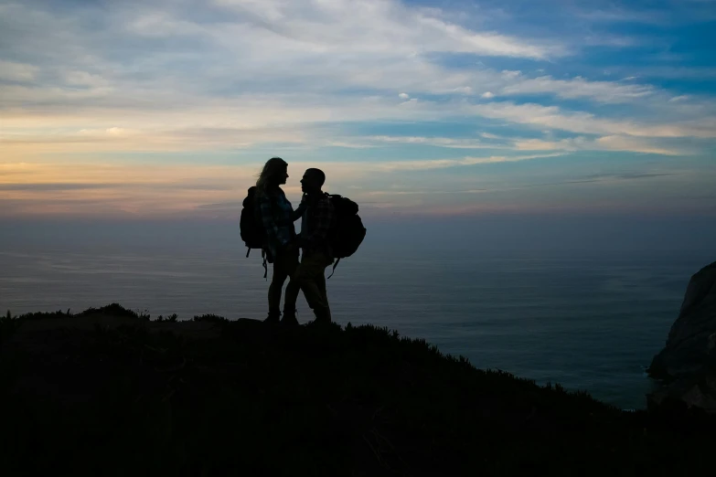 two people hiking up a cliff in the middle of the day