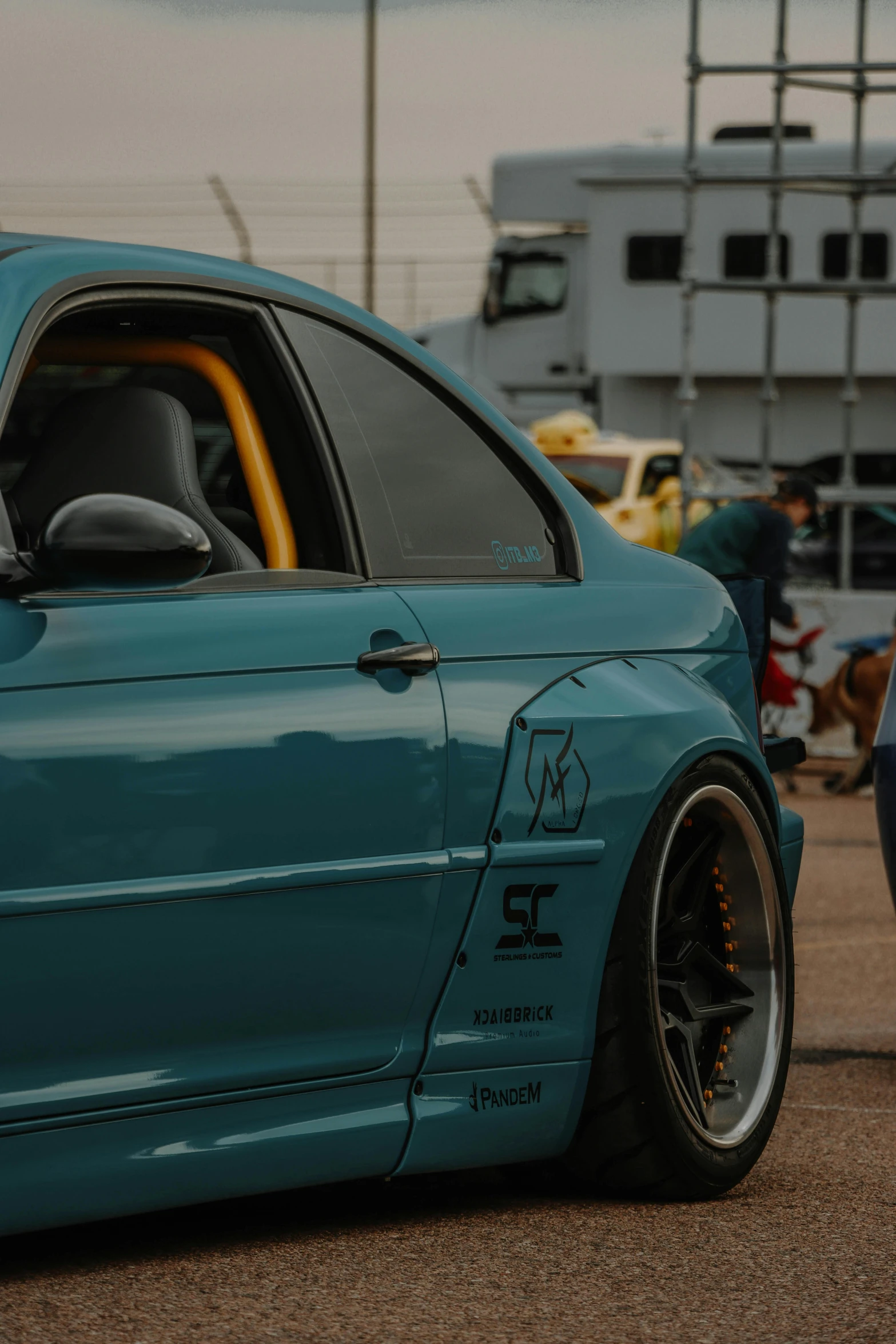 a close up of a blue sport car parked near a boat