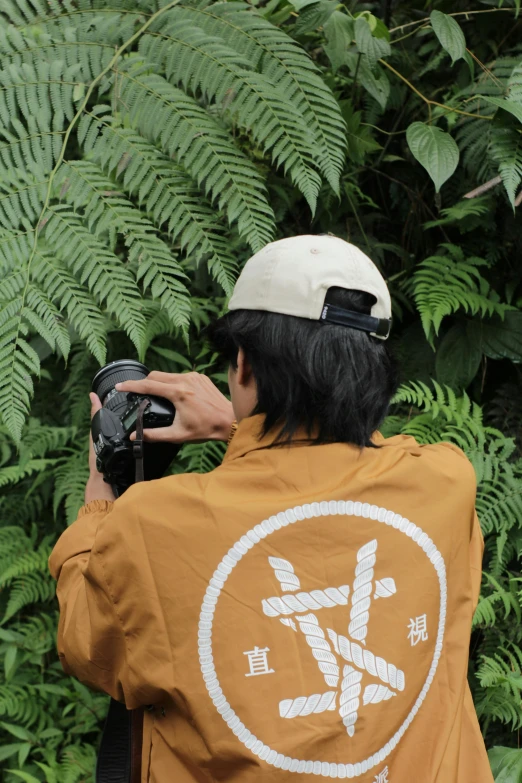 a man wearing an orange shirt and hat holding a camera