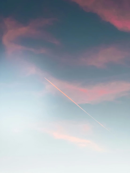 a jet airplane flying through the sky with a contrail above